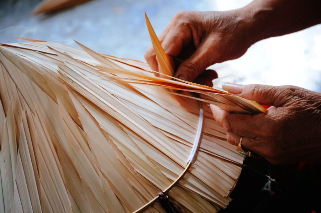 Close-up shot of an artisan sewing palm leaves.