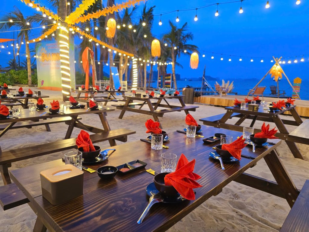 Beach BBQ setup with lanterns and seafood