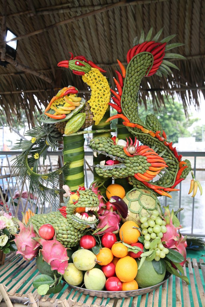 Close-up of offerings on boats (flowers, wine, and fruits).