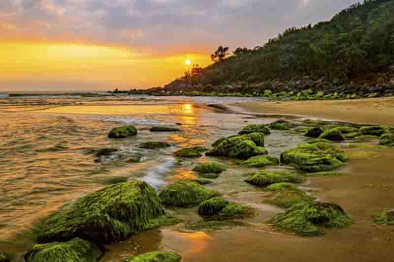 Sunrise view of Nam O Reef with green moss-covered rocks.