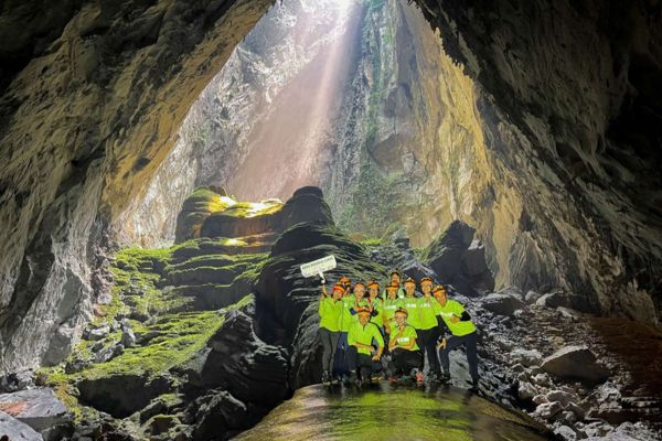 Tourists in trekking outfits smiling and exploring the cave interior.