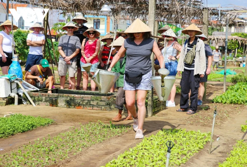Close-up of tourists watering plants with bamboo tools.