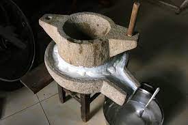 Tourists grinding rice batter or spreading it over a steaming pot.