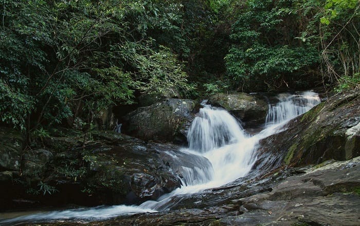 Wide shot of Ba Deo Waterfall with forest backdrop.