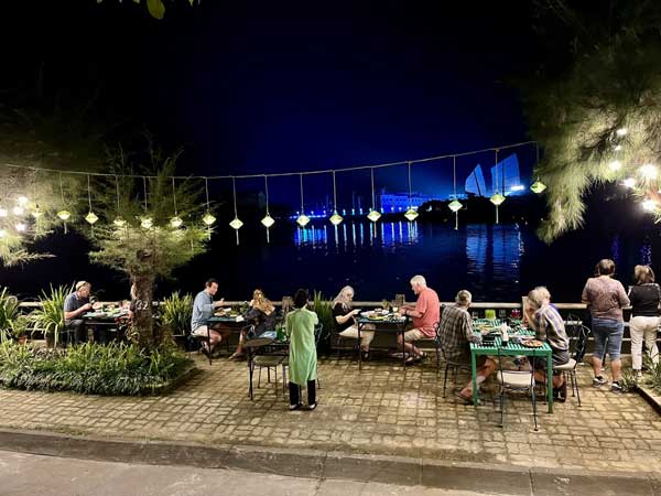 Travelers dining riverside.