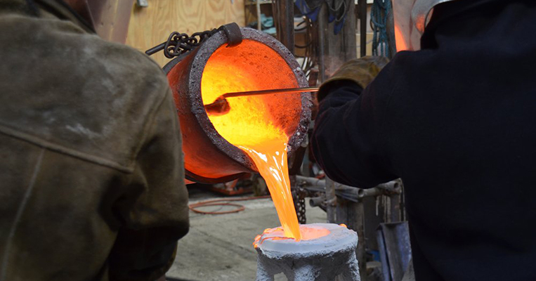 Artisans pouring molten bronze into molds.