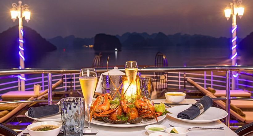 Tourists dining on the boat under starry sky.