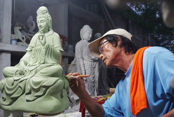 Local artisan carving a Buddha statue.