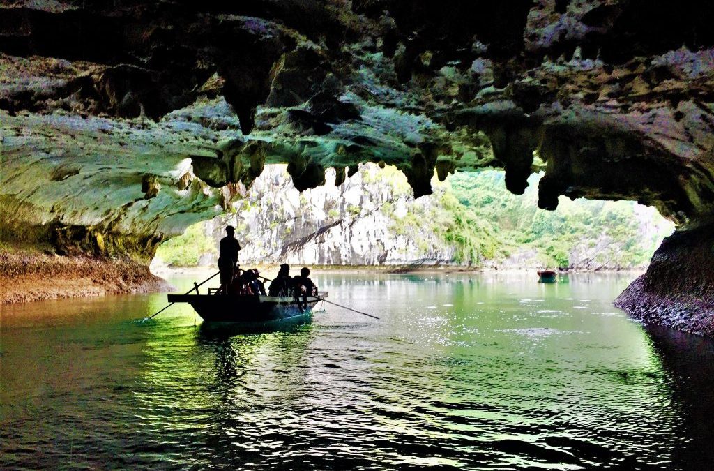 Tourists riding a wooden boat toward the cave entrance
