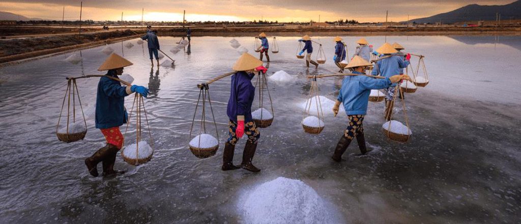 Travelers carrying salt using traditional bamboo poles.