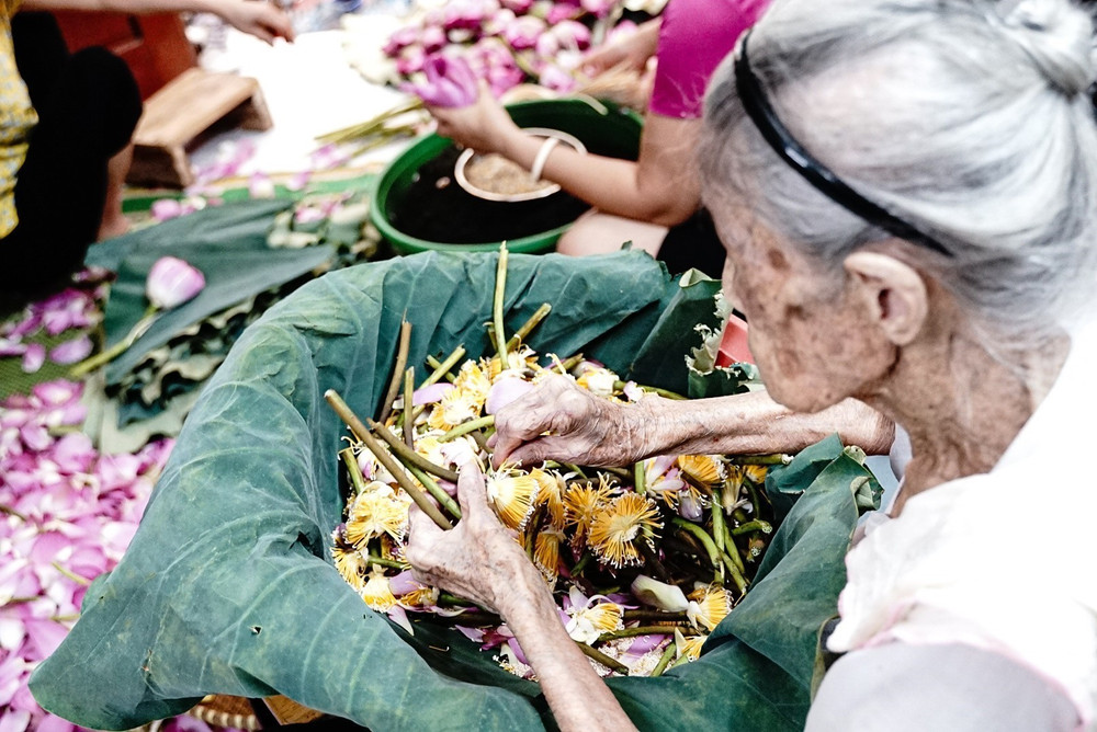 A local artisan infusing tea with lotus petals in traditional clay jars.
