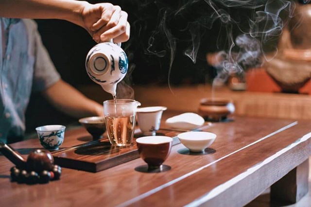 Tourists enjoying a tea ceremony in a wooden pavilion.