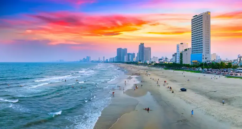 Wide-angle shot of Hoanh Son Beach with turquoise water and mountain backdrop